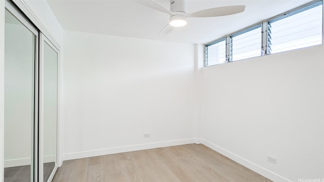 unfurnished bedroom featuring ceiling fan, a closet, baseboards, and light wood-style floors