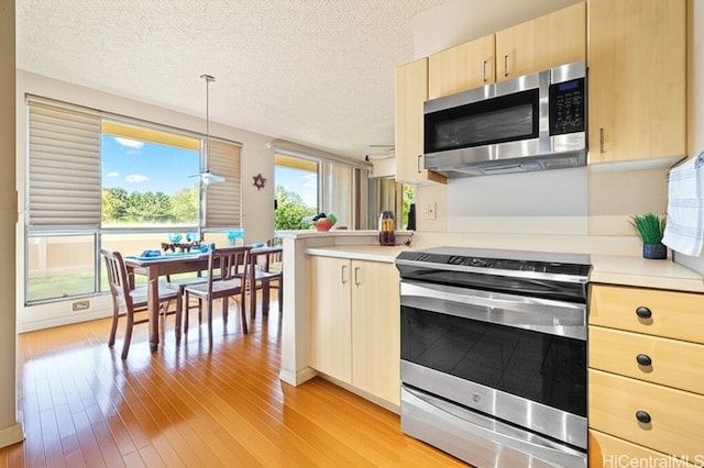 91-1012 Laaulu St Unit 28A, Ewa Beach, HI 96706 - kitchen with stainless steel appliances, light brown cabinets, light countertops, light wood-type flooring, and a textured ceiling