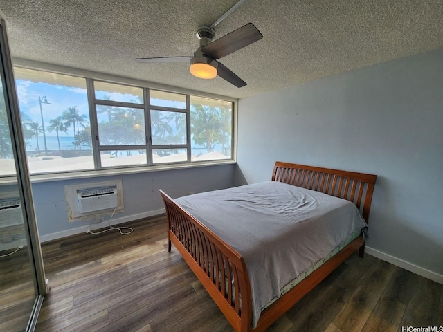 2500 Kalakaua Ave Unit 201, Honolulu, HI 96815 - bedroom featuring a textured ceiling, wood finished floors, baseboards, and an AC wall unit
