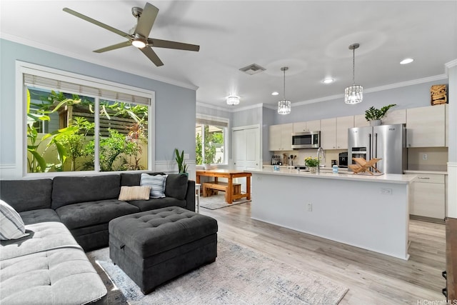 living room featuring a ceiling fan, light wood-type flooring, visible vents, ornamental molding, and recessed lighting