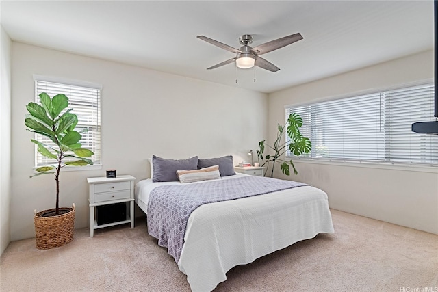 bedroom featuring light colored carpet, multiple windows, and a ceiling fan