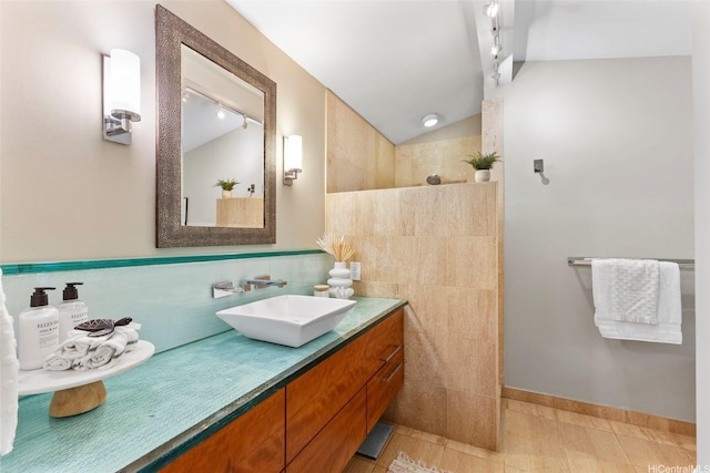 2055 Alihilani Pl, Honolulu, HI 96822 - bathroom with vaulted ceiling, walk in shower, tile walls, vanity, and tile patterned floors