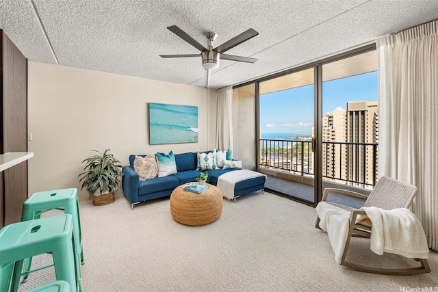 living area featuring a ceiling fan, a wall of windows, a textured ceiling, and carpet floors