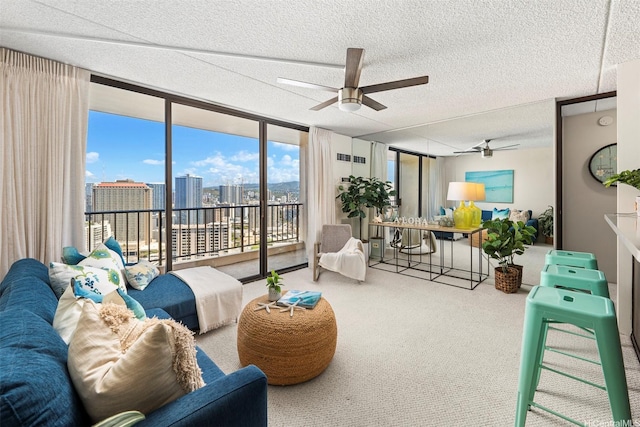 living room featuring carpet, expansive windows, ceiling fan, and a textured ceiling