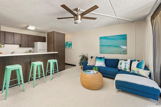 living room featuring ceiling fan, a textured ceiling, and carpet