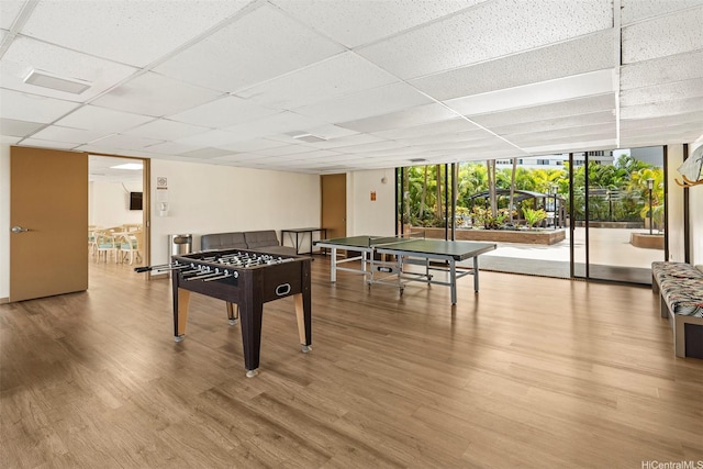 game room featuring a paneled ceiling, floor to ceiling windows, and wood finished floors