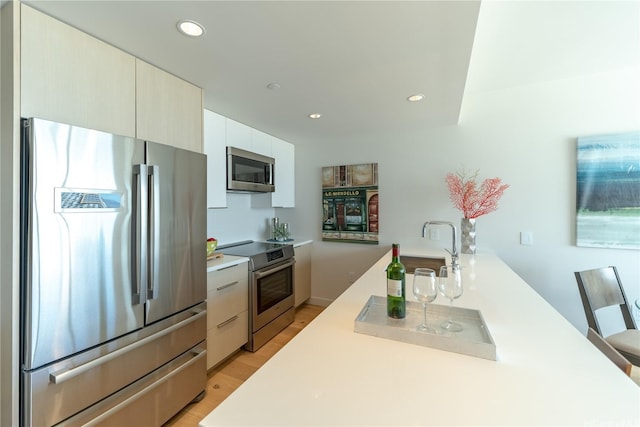 kitchen with stainless steel appliances, light countertops, light wood-style floors, a sink, and recessed lighting