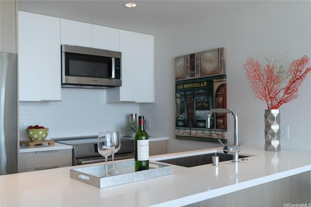 kitchen featuring stainless steel appliances, a sink, white cabinetry, tasteful backsplash, and recessed lighting