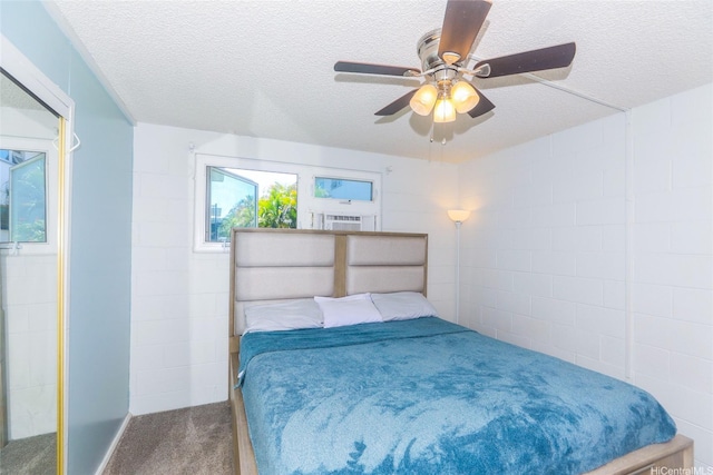 bedroom featuring a textured ceiling, concrete block wall, a ceiling fan, and carpet floors