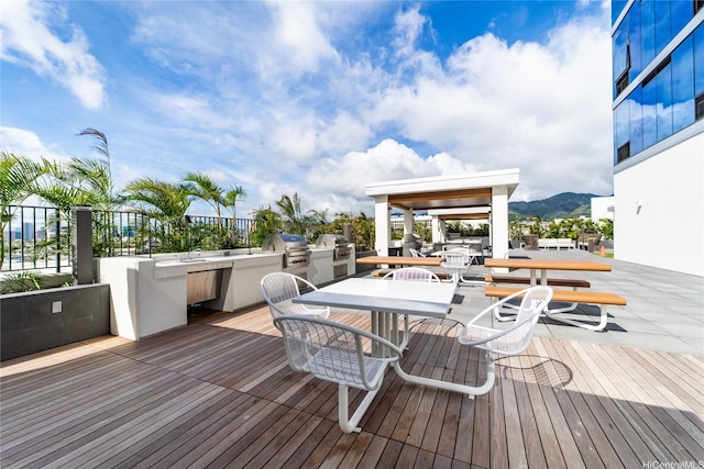 629 Keeaumoku St Unit 2205, Honolulu, HI 96814 - wooden terrace featuring an outdoor kitchen, outdoor dining space, a mountain view, a sink, and grilling area
