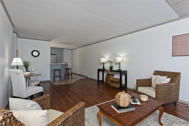 living area with baseboards, a textured ceiling, and wood finished floors