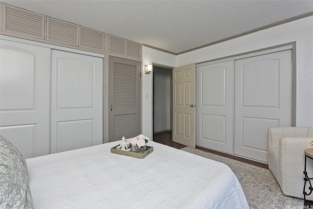 bedroom featuring multiple closets, crown molding, and a textured ceiling