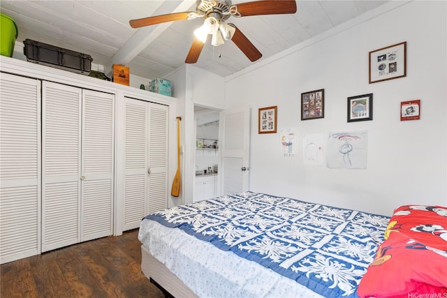 bedroom featuring dark wood-style floors, ceiling fan, wood ceiling, multiple closets, and vaulted ceiling with beams