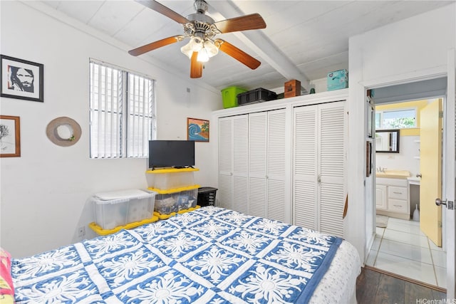 bedroom with a ceiling fan, lofted ceiling with beams, two closets, and wood finished floors
