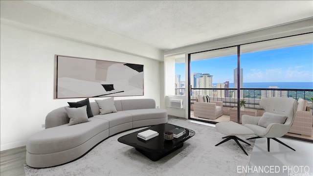 living room with a textured ceiling, a city view, wood finished floors, baseboards, and cooling unit