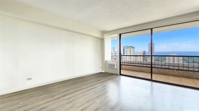 empty room with baseboards, wood finished floors, a view of city, and cooling unit