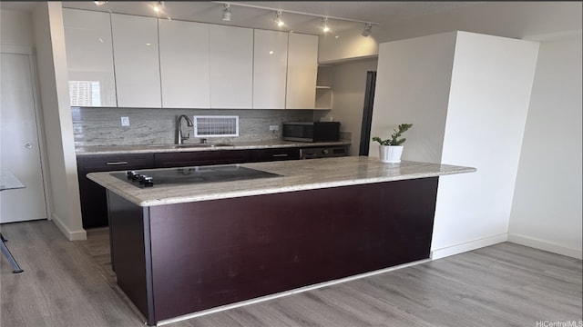kitchen with a sink, rail lighting, black electric cooktop, modern cabinets, and stainless steel microwave