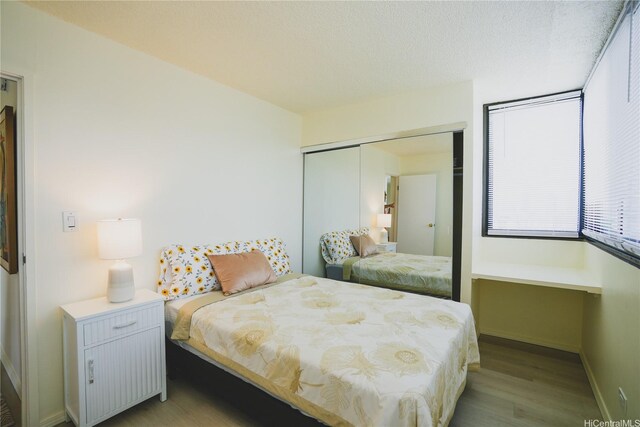 bedroom featuring wood finished floors, a closet, and baseboards