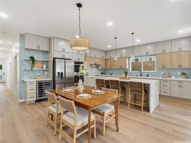 dining space featuring beverage cooler, light wood-type flooring, and recessed lighting