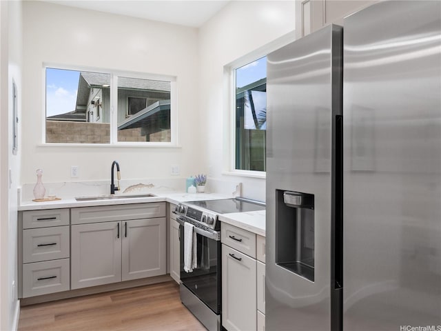 54-11 Pipilani Pl, Hauula, HI 96717 - kitchen with a sink, appliances with stainless steel finishes, light stone counters, gray cabinetry, and light wood-style floors