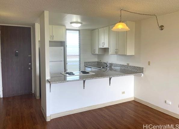 kitchen featuring a peninsula, baseboards, a breakfast bar area, and dark wood finished floors