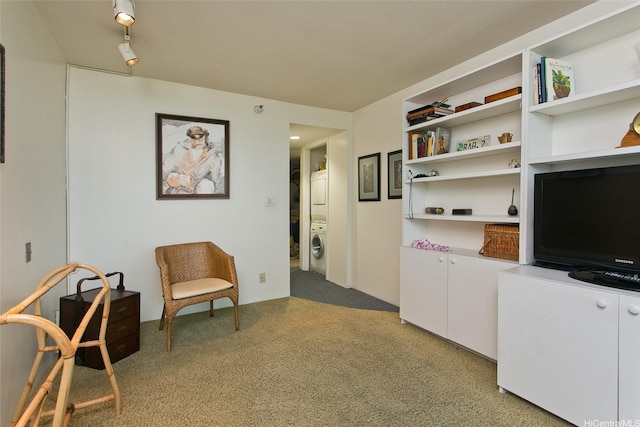 living area with estacked washer and dryer and light colored carpet