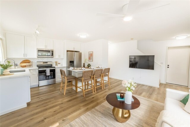 living area featuring light wood-type flooring and a ceiling fan