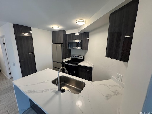 1441 Piikoi St Unit 206, Honolulu, HI 96822 - kitchen with stainless steel appliances, a sink, modern cabinets, a peninsula, and light wood finished floors