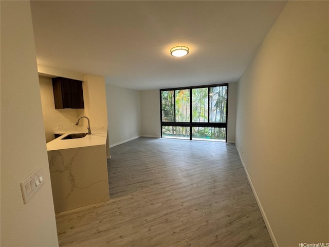 1441 Piikoi St Unit 206, Honolulu, HI 96822 - unfurnished living room featuring a sink, expansive windows, light wood-type flooring, and baseboards