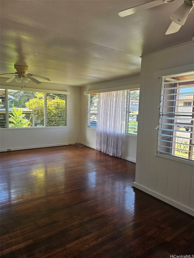spare room featuring a ceiling fan, dark wood-style flooring, and baseboards