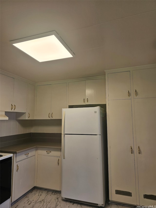 kitchen featuring dark countertops, marble finish floor, and white appliances