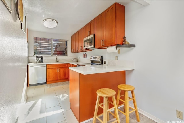 92-1044 Kanehoa Loop Unit 85, Kapolei, HI 96707 - kitchen with appliances with stainless steel finishes, a peninsula, a sink, a breakfast bar area, and light countertops