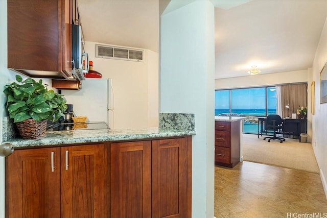 1088 Bishop St Unit 3706, Honolulu, HI 96813 - kitchen featuring a desk, brown cabinets, light stone countertops, freestanding refrigerator, and black electric stovetop