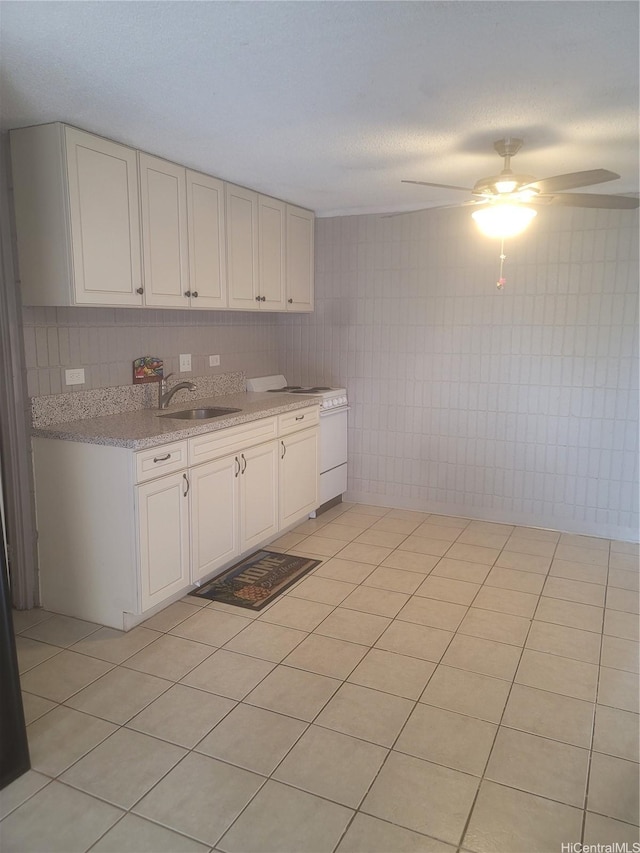 kitchen featuring a ceiling fan, light tile patterned floors, white electric stove, a sink, and decorative backsplash