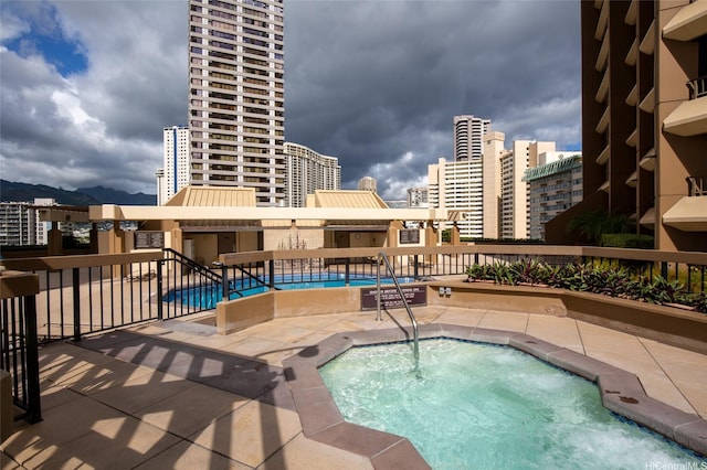community pool featuring a community hot tub, a patio area, and a view of city