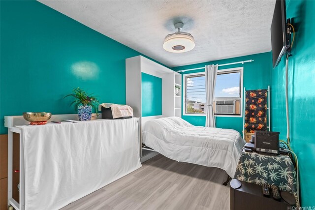 3003 Ala Napuaa Pl Unit 401, Honolulu, HI 96818 - bedroom with a textured ceiling, cooling unit, and wood finished floors