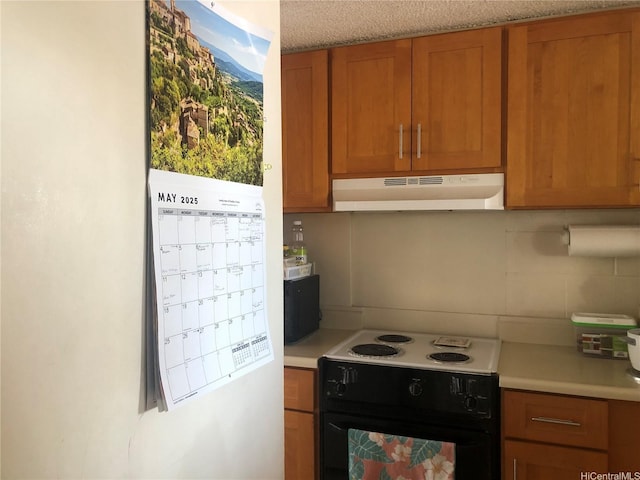 647 Kunawai Ln Unit A507, Honolulu, HI 96817 - kitchen with under cabinet range hood, light countertops, brown cabinetry, and black electric range oven