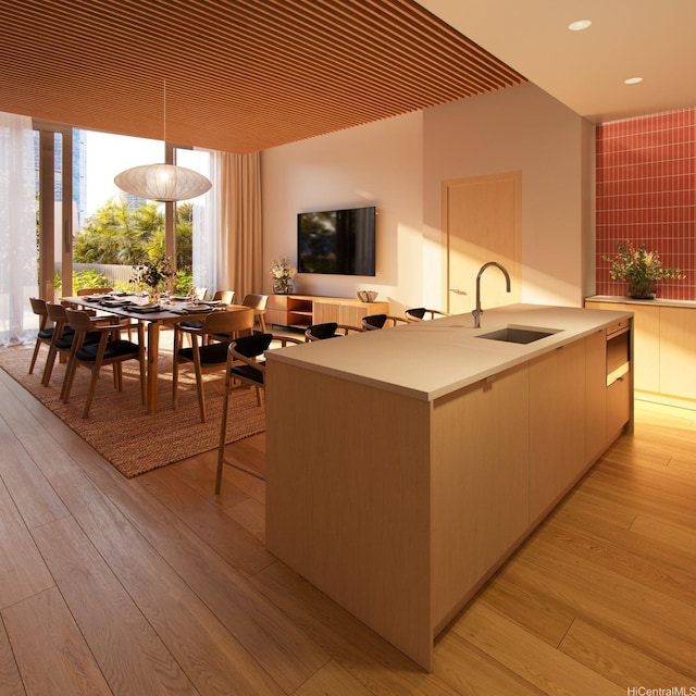 kitchen with a sink, light countertops, light wood-type flooring, modern cabinets, and recessed lighting