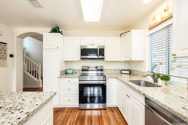 91-6414 Kapolei Pkwy, Ewa Beach, HI 96706 - kitchen featuring appliances with stainless steel finishes, a sink, light wood-style floors, white cabinetry, and light stone countertops
