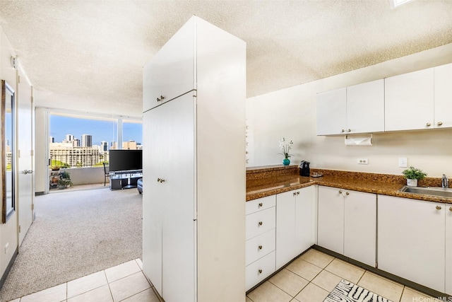 1805 Poki St Unit 1101, Honolulu, HI 96822 - kitchen featuring a sink, light tile patterned floors, a textured ceiling, white cabinetry, and dark countertops