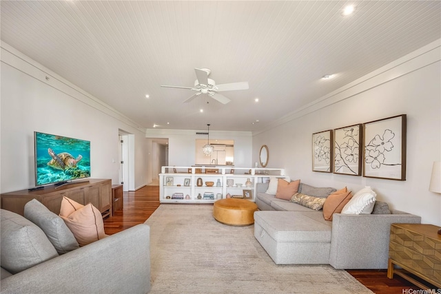 living area featuring wood finished floors, a ceiling fan, ornamental molding, and recessed lighting