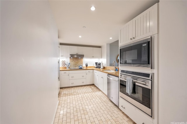 kitchen with black appliances, under cabinet range hood, recessed lighting, and a sink