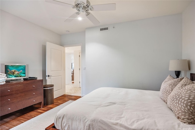 bedroom with ceiling fan, visible vents, and wood finished floors