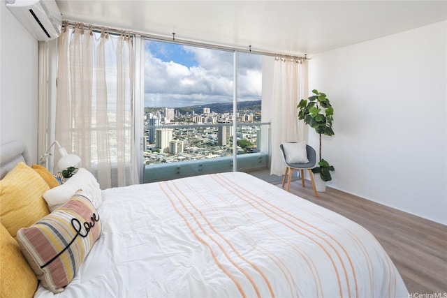 bedroom featuring a view of city, a wall mounted air conditioner, and wood finished floors