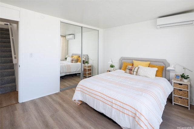bedroom featuring an AC wall unit, a closet, and wood finished floors