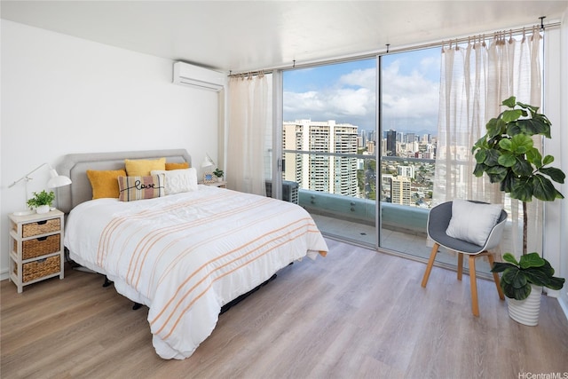 bedroom featuring a wall of windows, a city view, a wall mounted AC, and wood finished floors