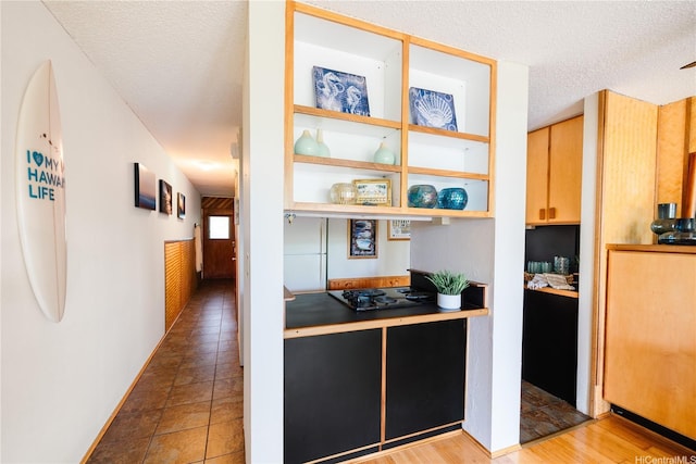 kitchen with black electric cooktop, tile patterned floors, and a textured ceiling