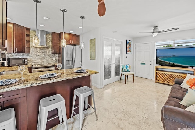 75 Kihapai St Unit 11, Kailua, HI 96734 - kitchen featuring stainless steel appliances, wall chimney exhaust hood, ceiling fan, backsplash, and a peninsula