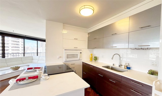 kitchen featuring a sink, electric range, modern cabinets, white microwave, and light countertops