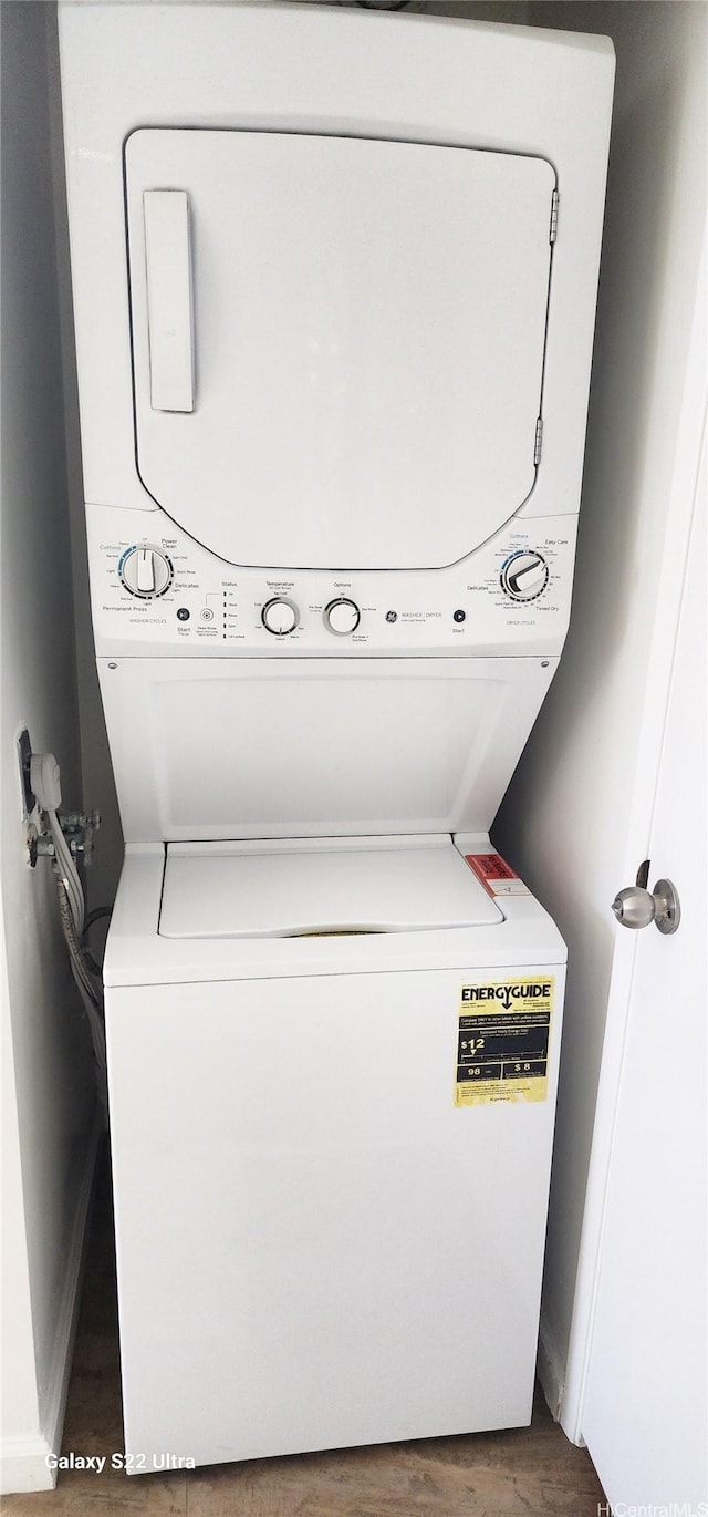 laundry room featuring stacked washing maching and dryer, laundry area, and wood finished floors